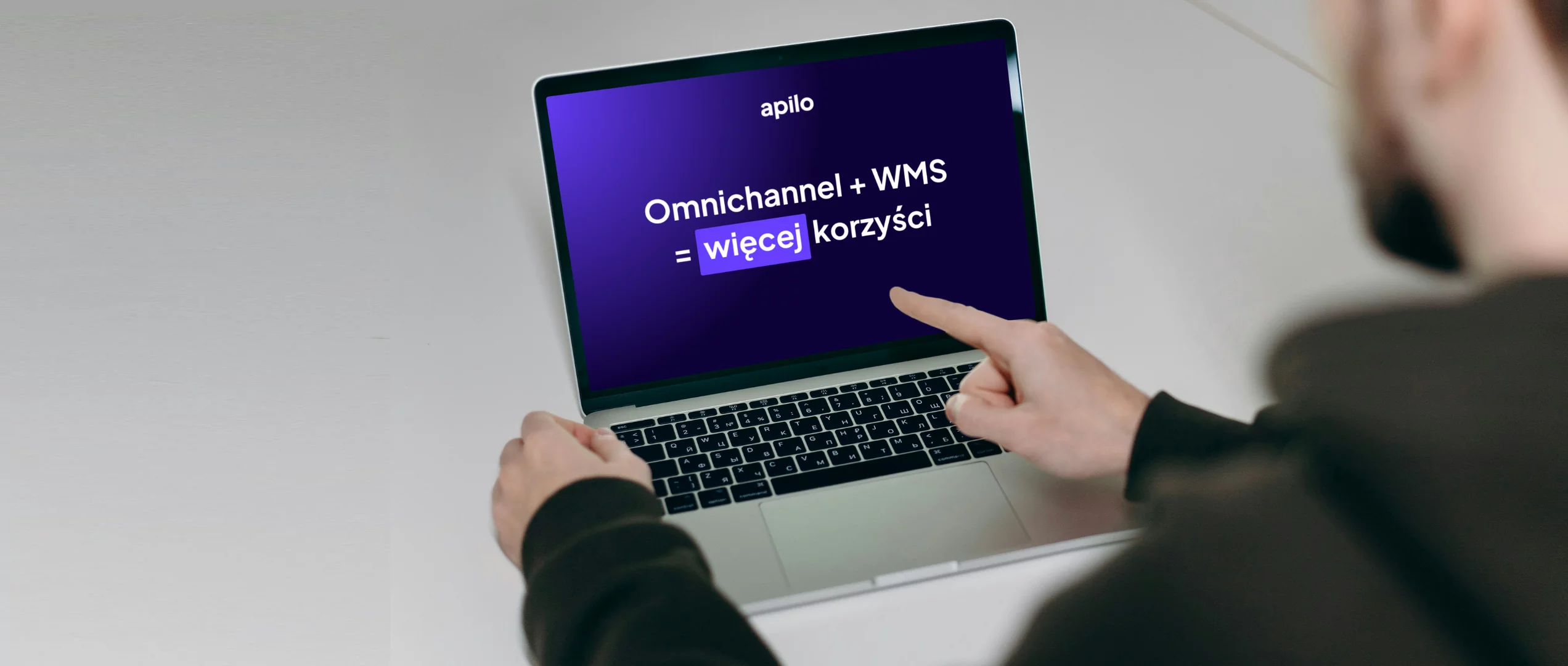 Mężczyzna wskazujący palcem na ekran laptopa, gdzie znajdują się informacje o korzyściach z integracji omnichannel z wms
